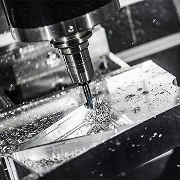 Close-up of a CNC machine cutting through a metal block, producing metal shavings during precision machining.